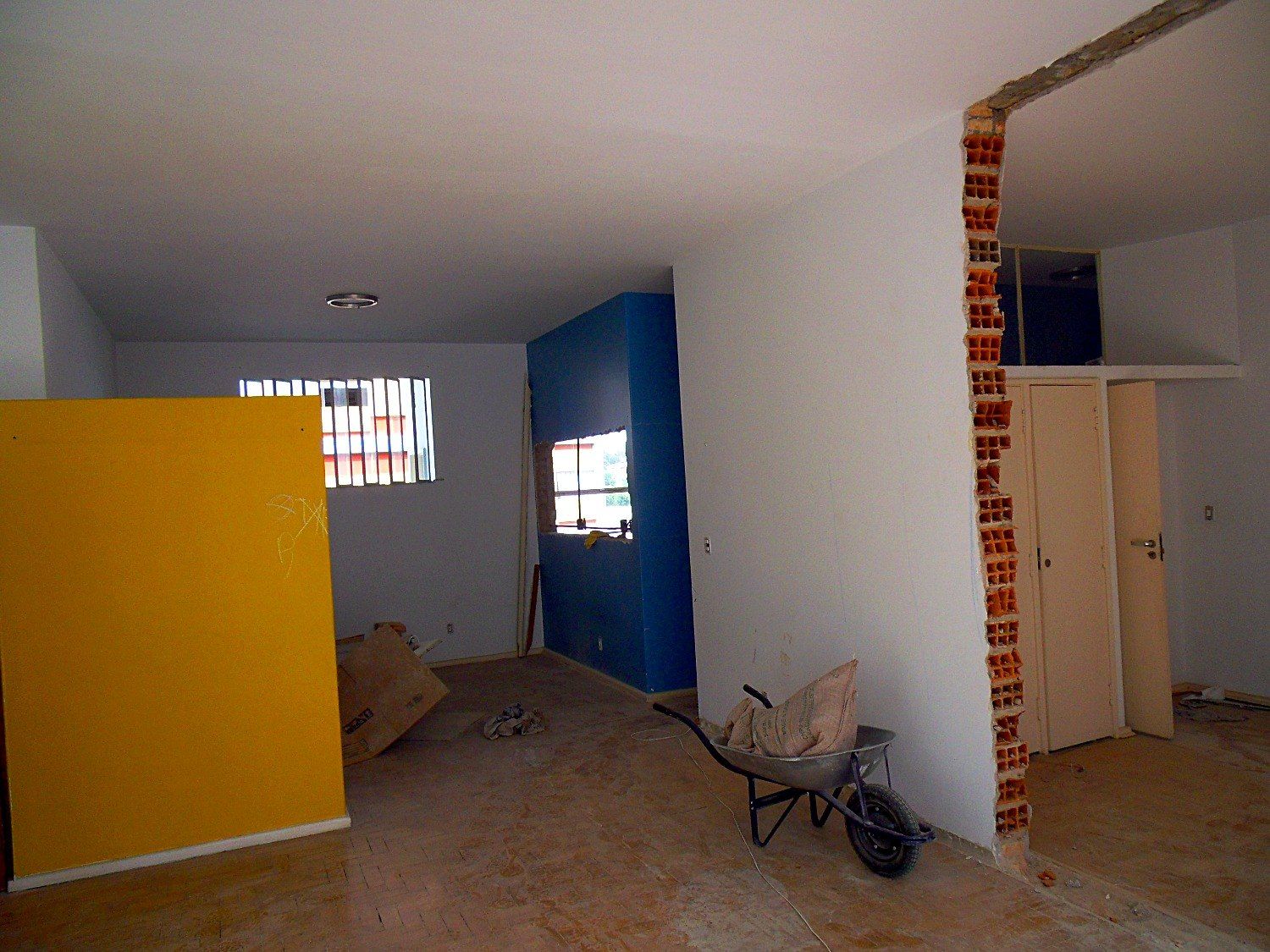 Apartamento antes da reforma, com painéis amarelo e azul e piso de tacos