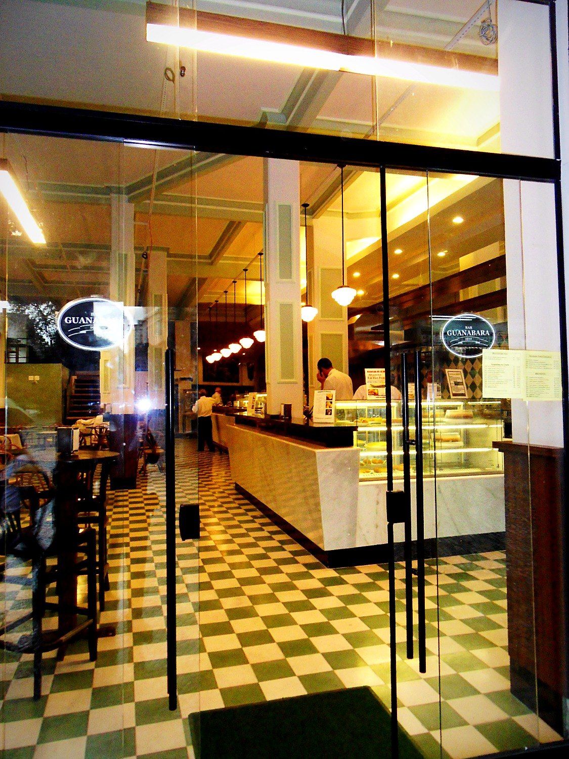 Porta de vidro do restaurante, balcão de mármore e piso xadrez verde e branco