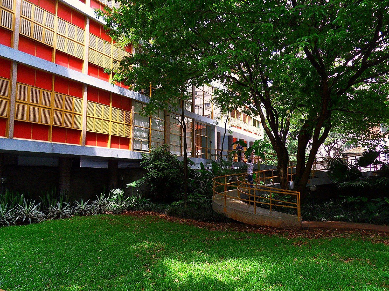 Jardim interno do edifício, com a fachada colorida ao fundo