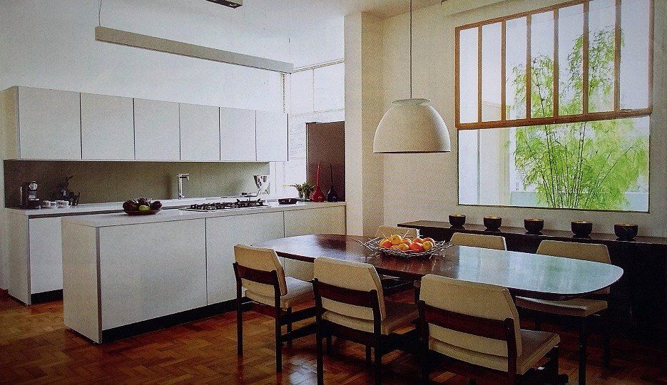Cozinha e sala de jantar com armários brancos e piso de tacos
