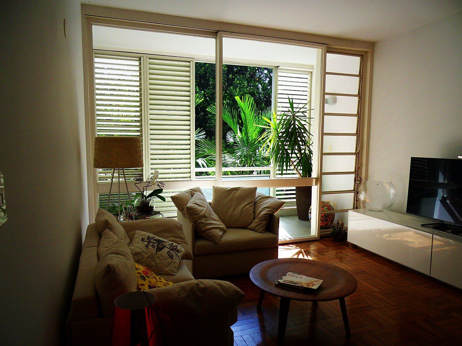 Estar com sofá e mesa de centro diante do caixilho original com venezianas