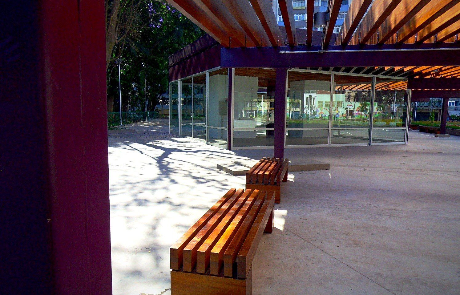 Bancos ripados de madeira e vitrine da floricultura sob o pergolado