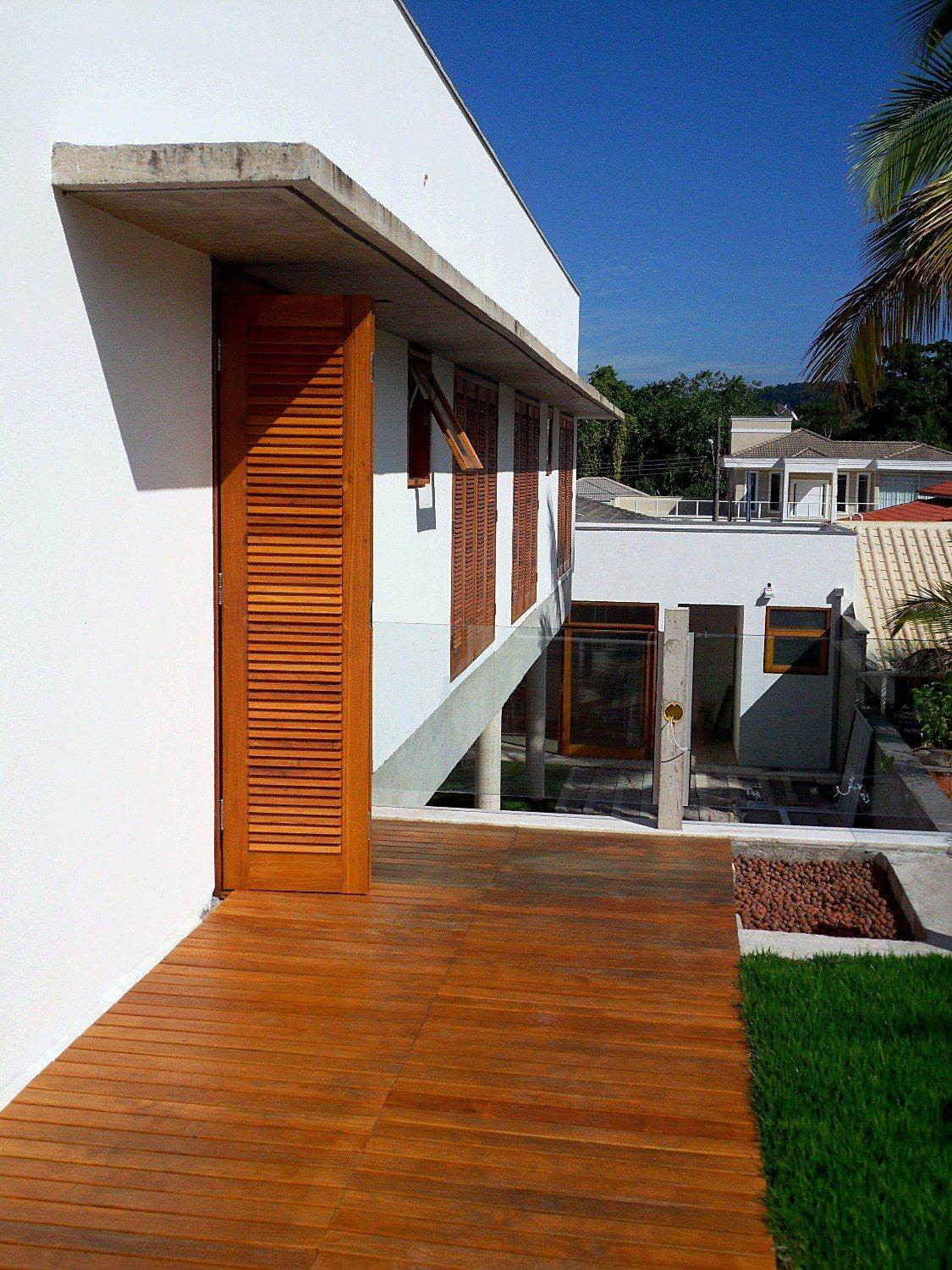 Terraço superior com deck de madeira, veneziana aberta e marquise de concreto
