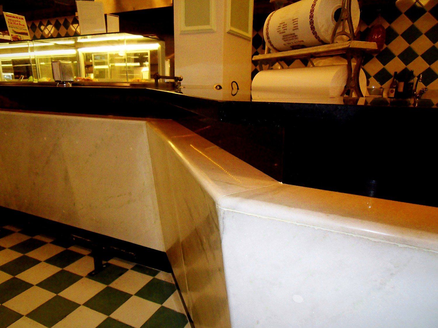 Detalhe do balcão: mármore branco, tampo em granito preto e piso xadrez