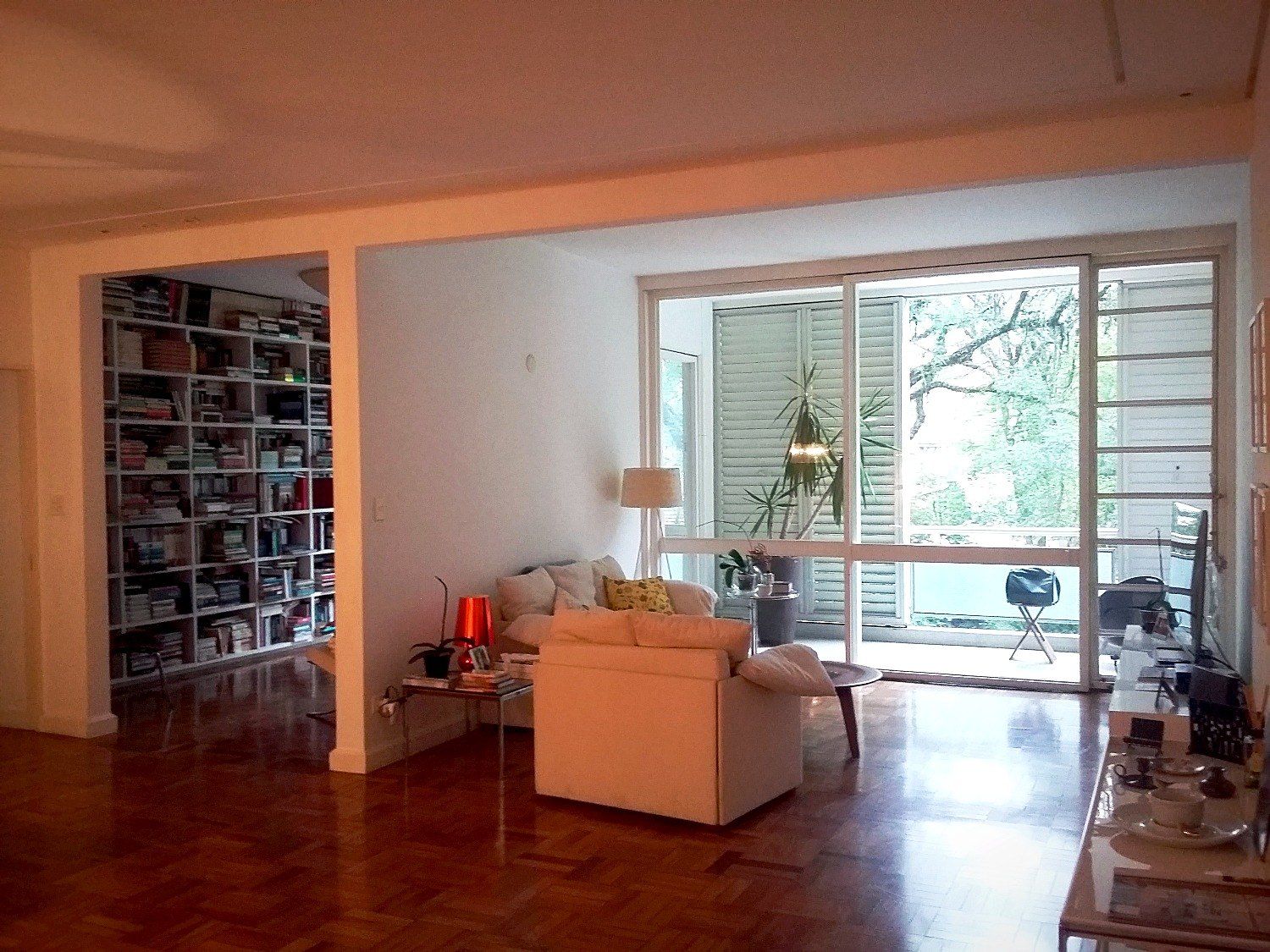 Sala com biblioteca de piso a teto e vista para a varanda e as árvores