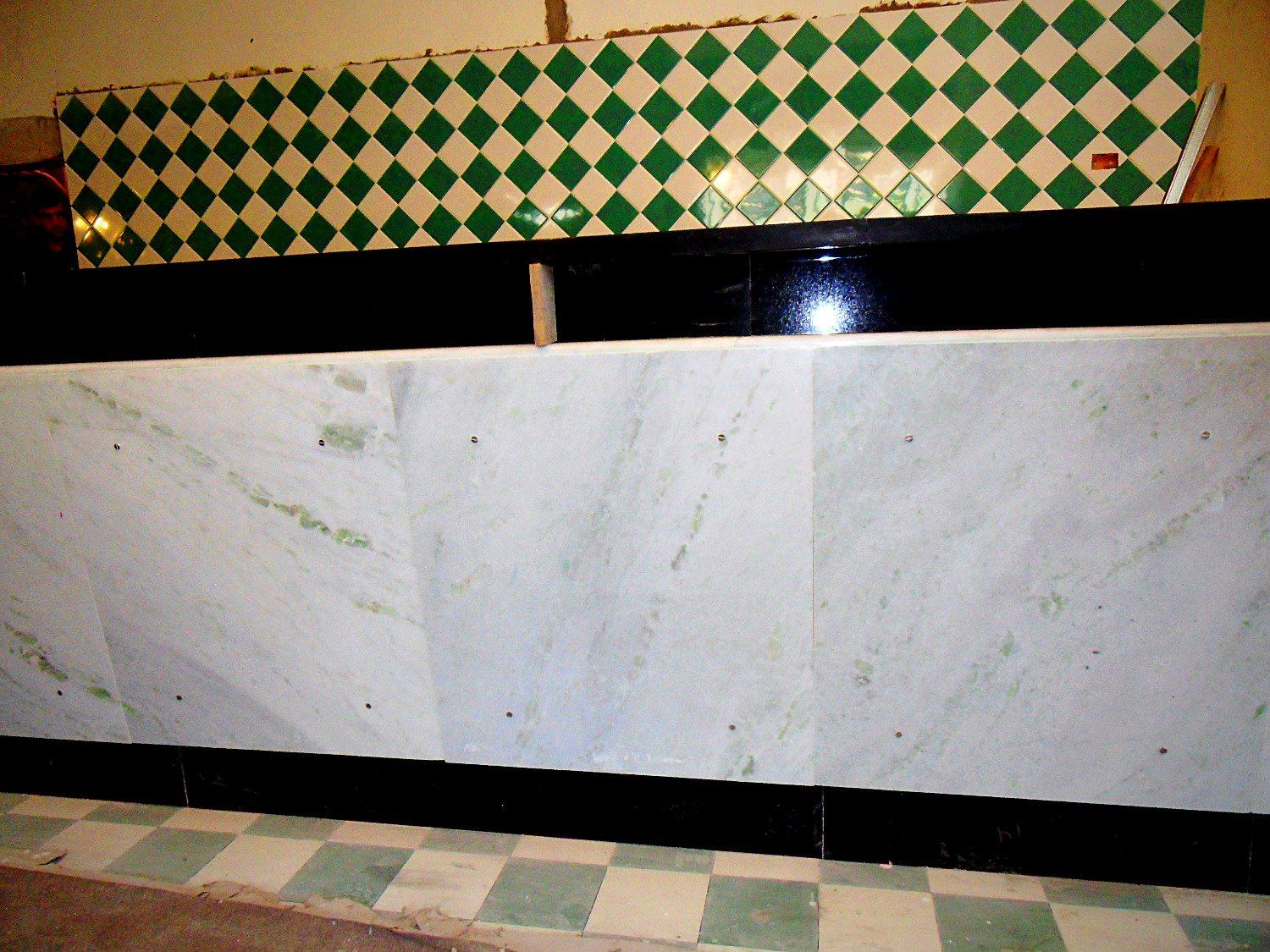 Balcão revestido em mármore branco, faixa de granito preto e azulejos em losango