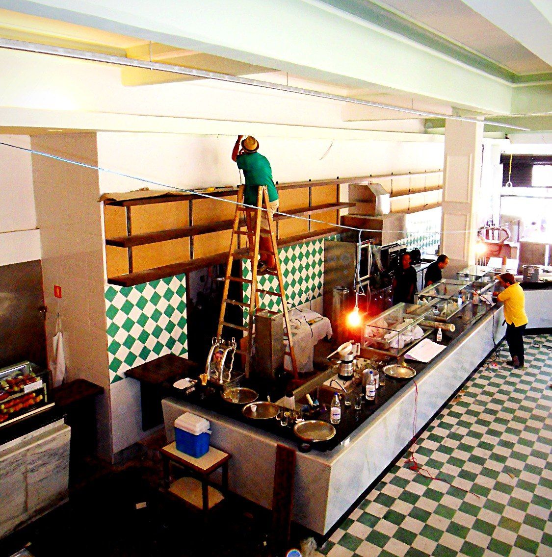 Montagem das prateleiras do bar sobre o balcão, com operário na escada