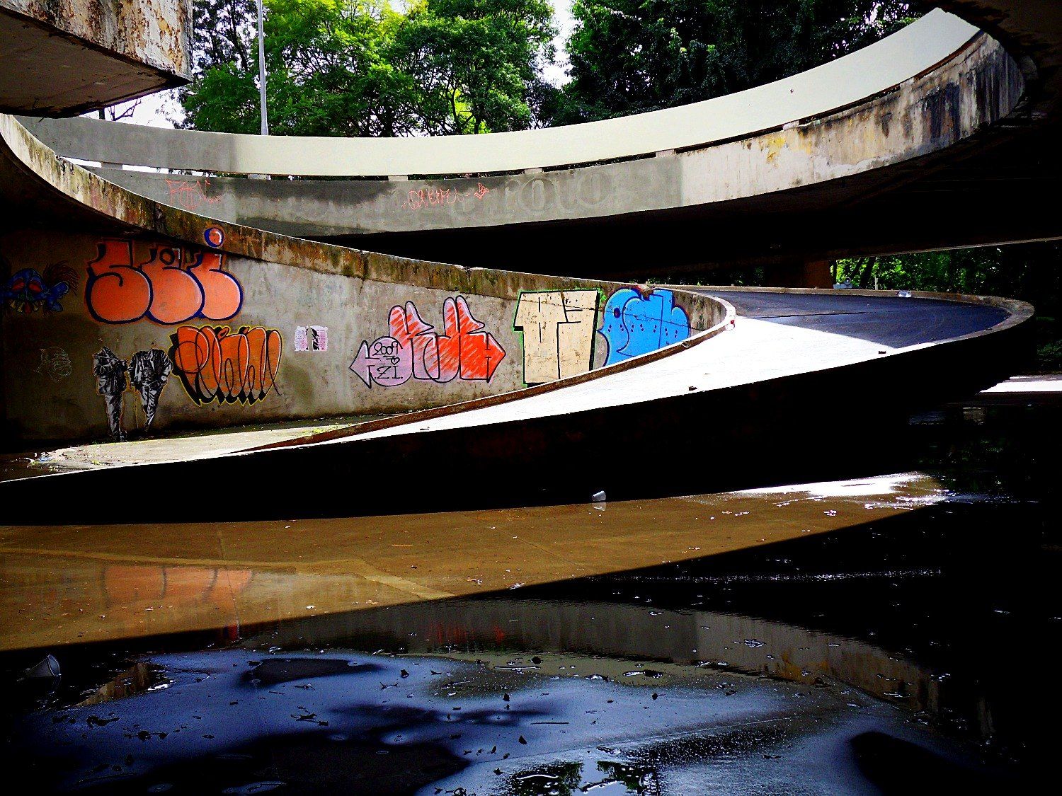 Rampa curva de concreto da antiga praça com grafites