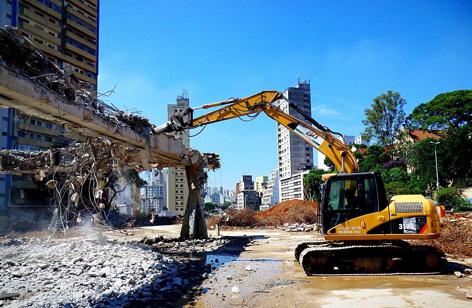 Escavadeira removendo entulho da estrutura demolida