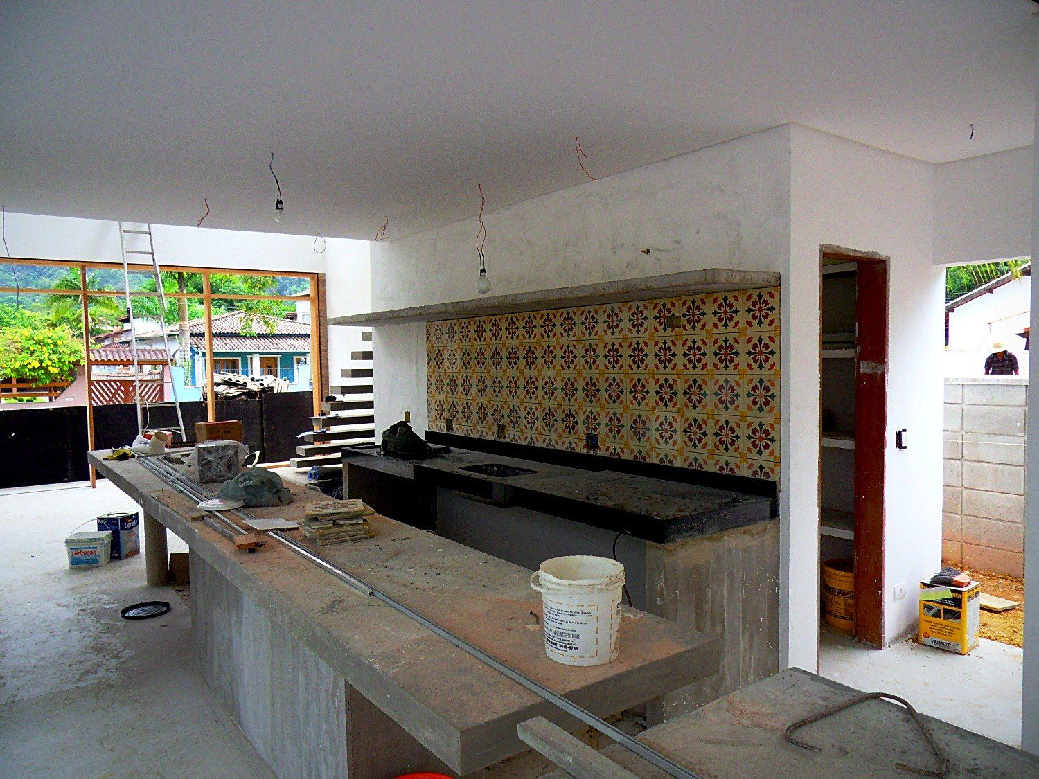Cozinha com balcão de concreto e painel de azulejos estampados